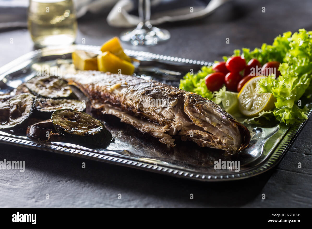 Roasted fish on dish with fresh and grilled vegetable. Stock Photo