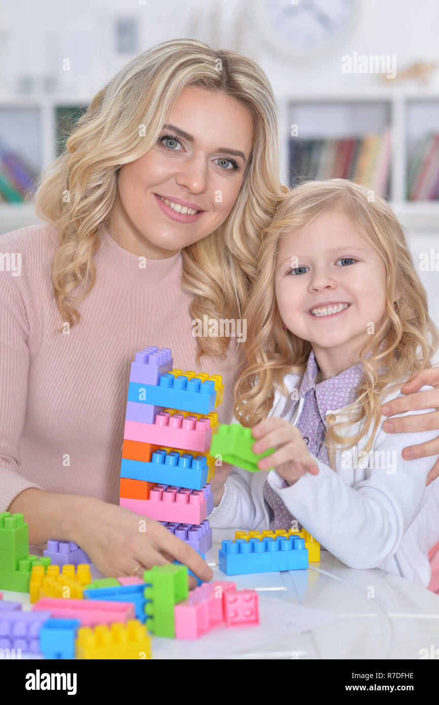 Little girl and mother playing with colorful plastic blocks at h Stock Photo