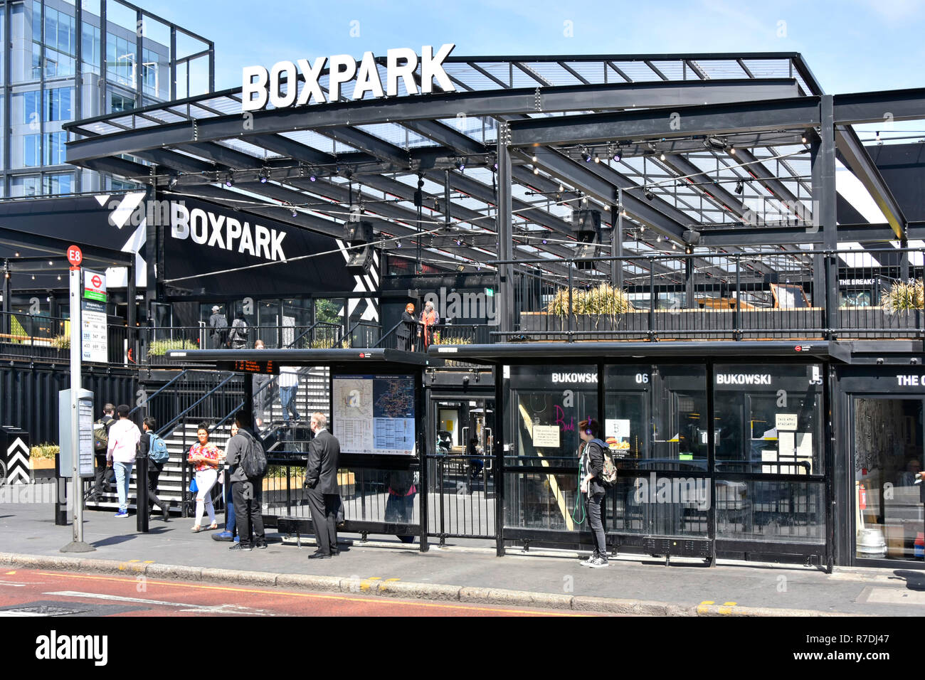 London street scene people wait at public transport bus stop at Boxpark food & retail business built from shipping containers East Croydon England UK Stock Photo