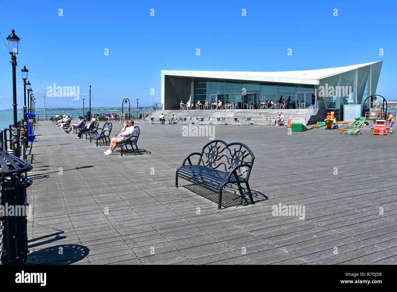 Southend Pier seats people relaxing in summer sunshine at pier head modern Royal Pavilion cafe outdoor tables in River Thames estuary Essex England UK Stock Photo
