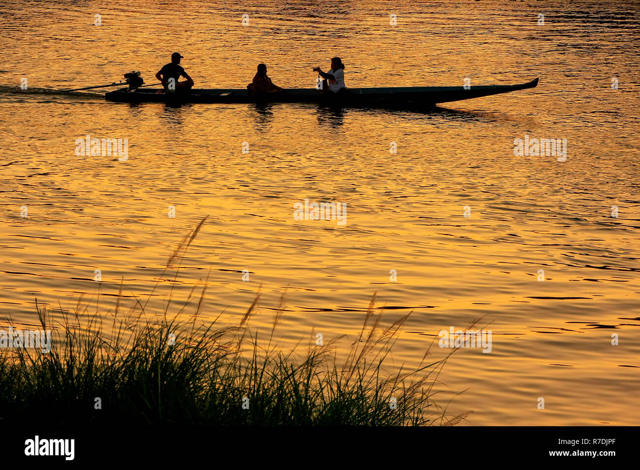 Silhouetted people in  a boat at sunset on Nam Song River in Vang Vieng, Laos. Vang Vieng is a popular destination for adventure tourism in a limeston Stock Photo