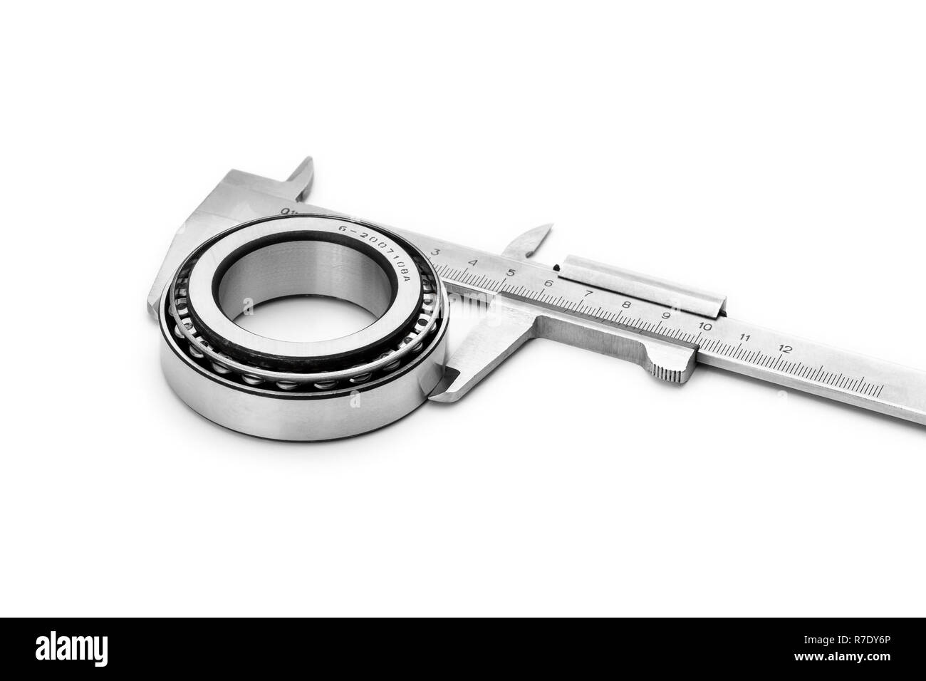 Measuring the diameter of a roller bearing with a caliper. Close-up on a white background. Stock Photo