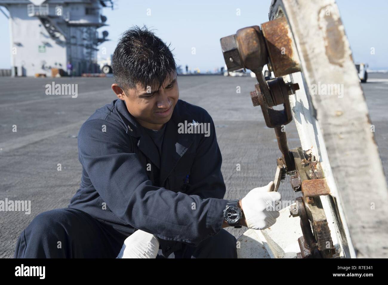 ATLANTIC OCEAN (May 17, 2017) Aviation Boatswain's Mate 3rd Class Ortiz Barreto, from Los Angeles, removes rust from a watertight hatch assembly on the flight deck of the aircraft carrier USS Dwight D. Eisenhower (CVN 69) (Ike). Ike is currently underway conducting engineering drills as part of the sustainment phase of the Optimized Fleet Response Plan (OFRP). Stock Photo