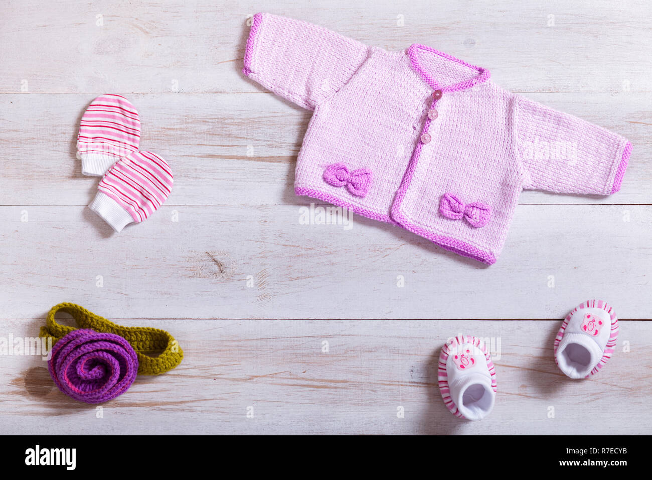 Baby clothes pink knitted tiny sweater cotton little mittens socks on white  wooden background, infant cloth set on table, child newborn fashion clothi  Stock Photo - Alamy