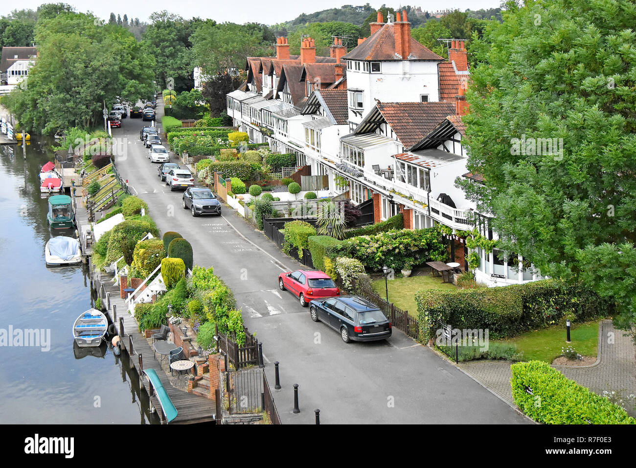 Looking down from above small boats moored on River Thames close to riverside house & car parking on private road Taplow Buckinghamshire England UK Stock Photo