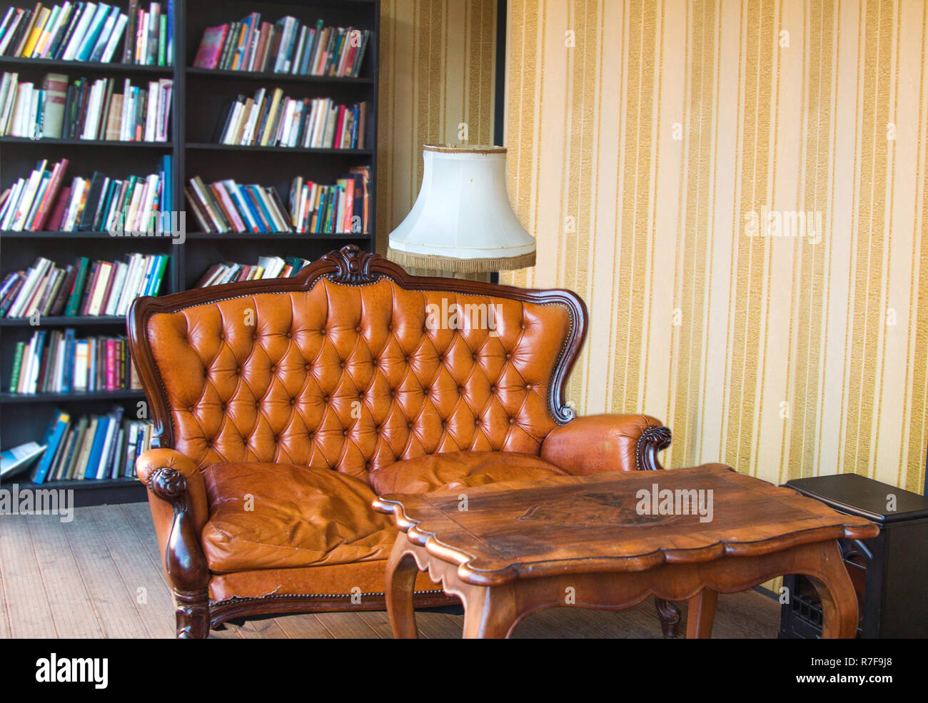 Classic interior room with books. Old antique leather arm chairs, table