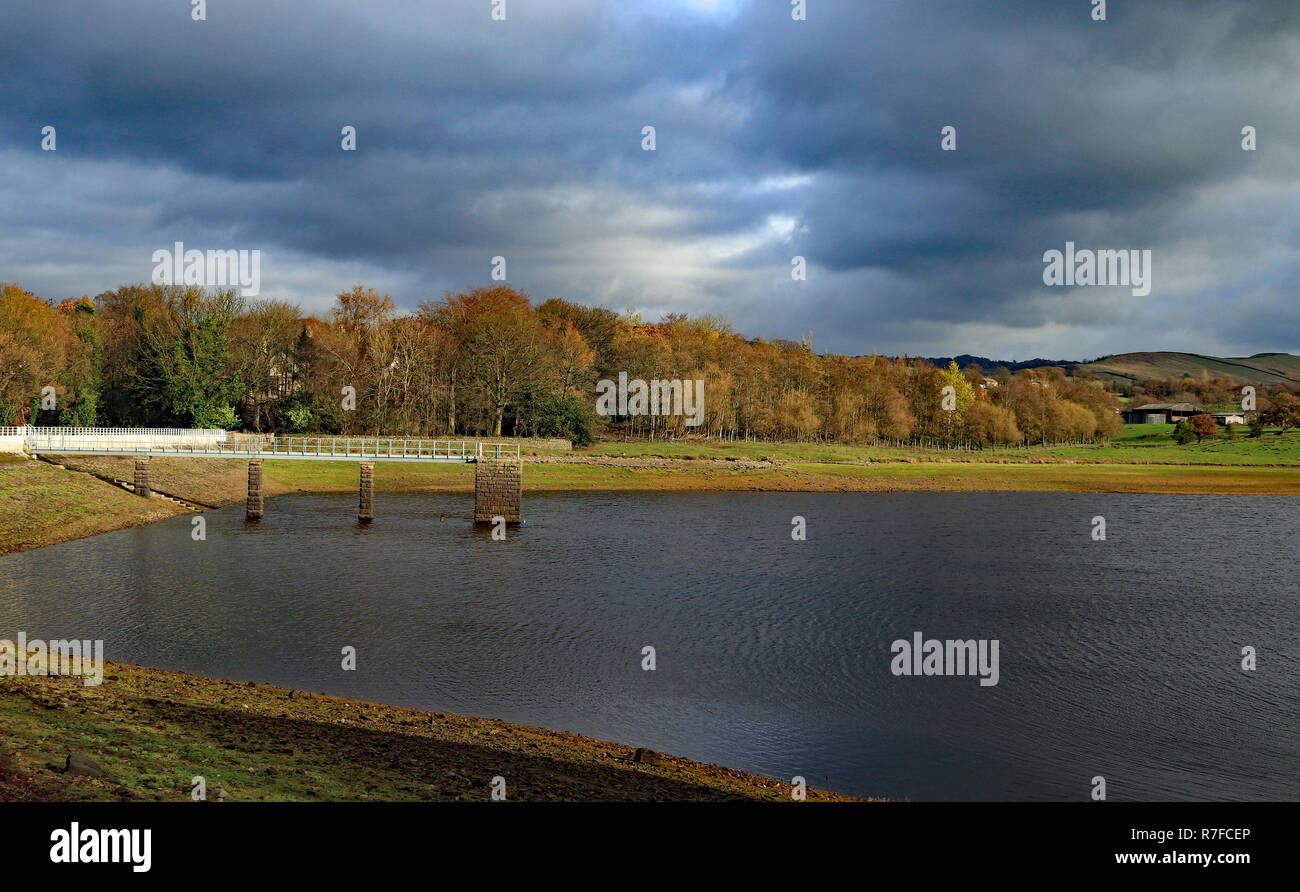Foulridge upper reservoir on a autumn morning has a back drop of dark storm clouds. As autumn draws on the water levels are still low after the summer Stock Photo