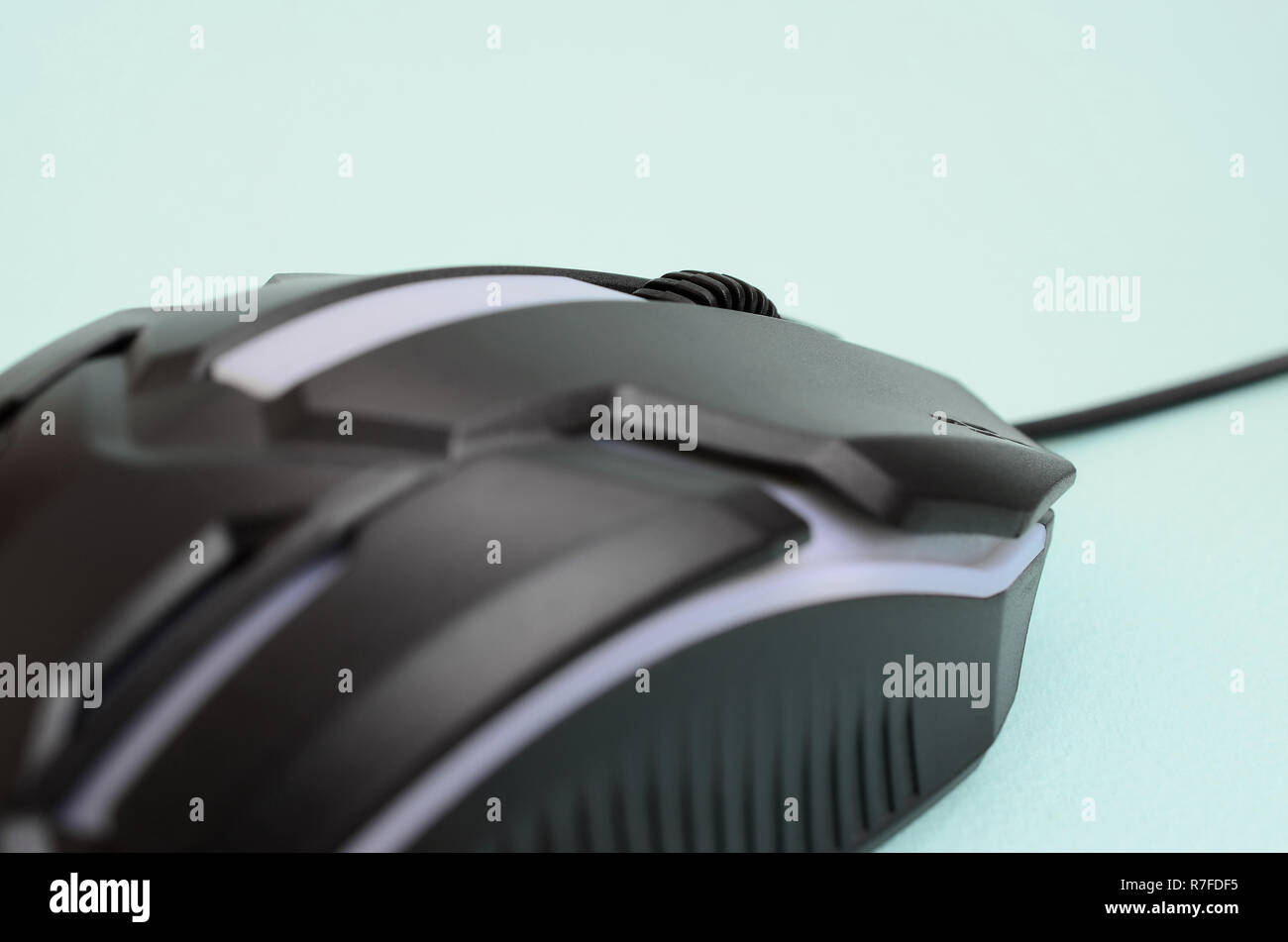 Closeup of a black gaming optical mouse on a blue background. Device ...