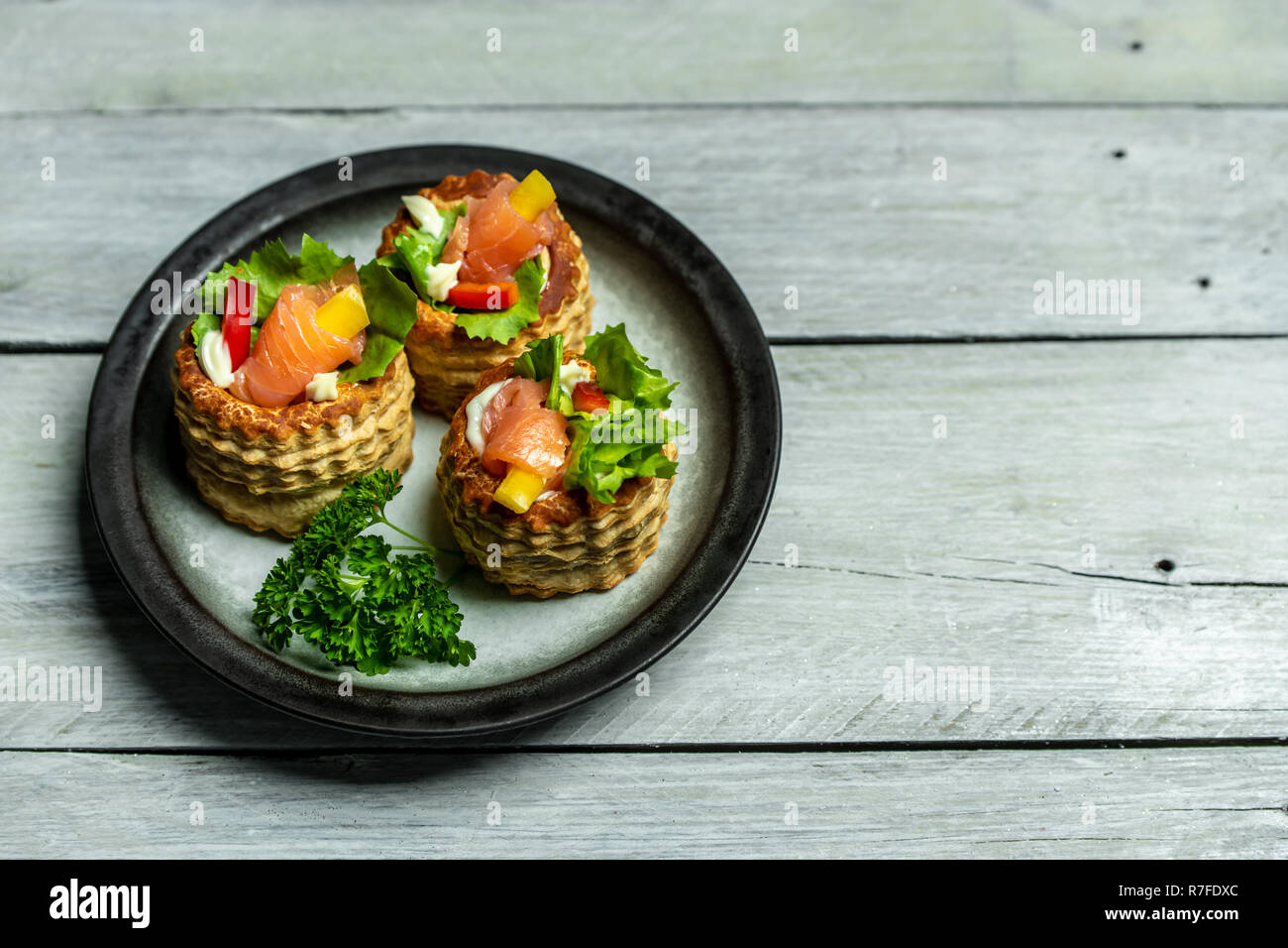 French cuisine, crunchy patties with lettuce and smoked salmon on a bright, rustic background Stock Photo