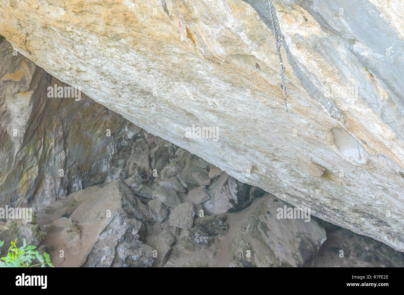 Natural climbing wall at the hillside of a rocky mountain. Carabiners ready to be used by the climbers. Soft background. Shaded spot area Stock Photo