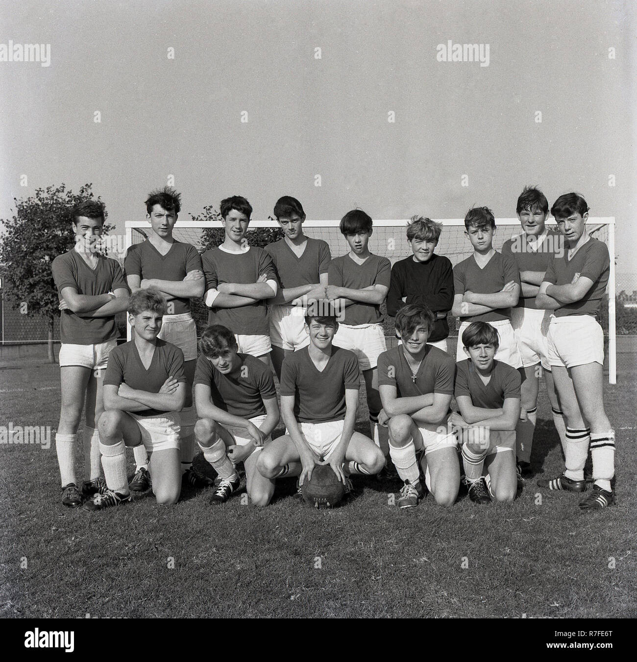 1965, young male footballers outside standing together for a team picture....v-neck shirts, polished boots, thick shin pads and look at that ball! Stock Photo