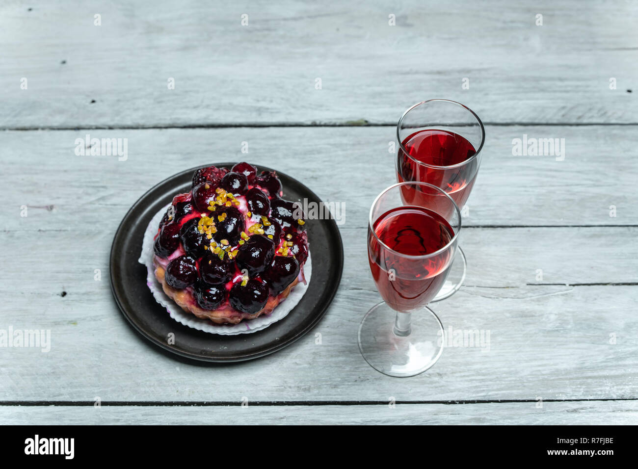 sweet meal for two red wine and cake with icing and fruits Stock Photo