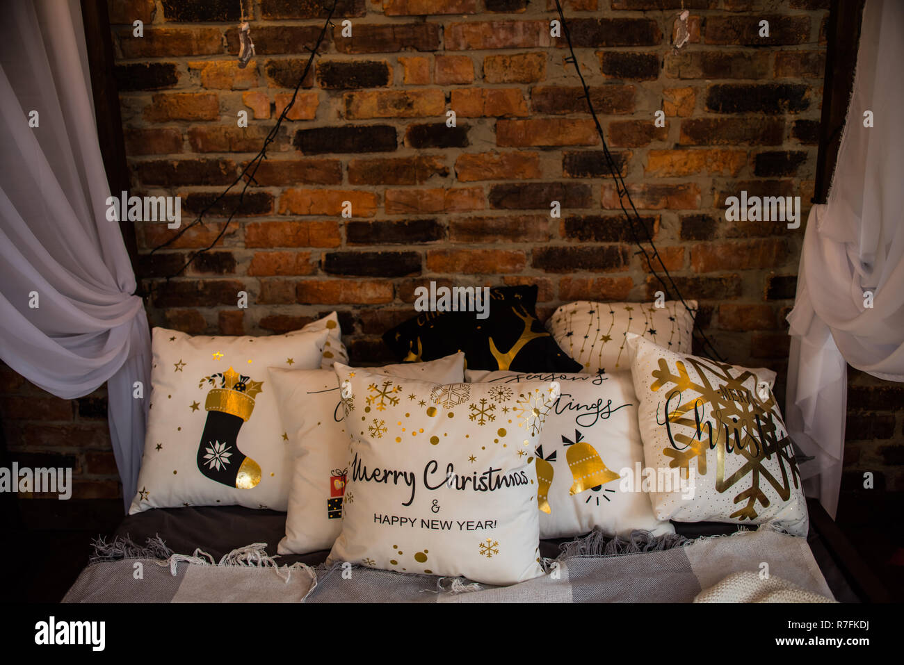 many different decorative pillows on bed baldachin brick wall. Stock Photo