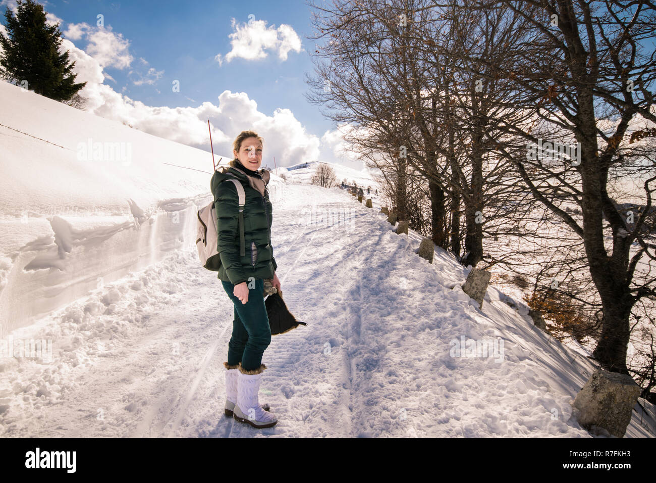 Trento, Italy - February 19, 2016: Young woman in a snowy mountain landscape on a beautiful sunny day. Stock Photo
