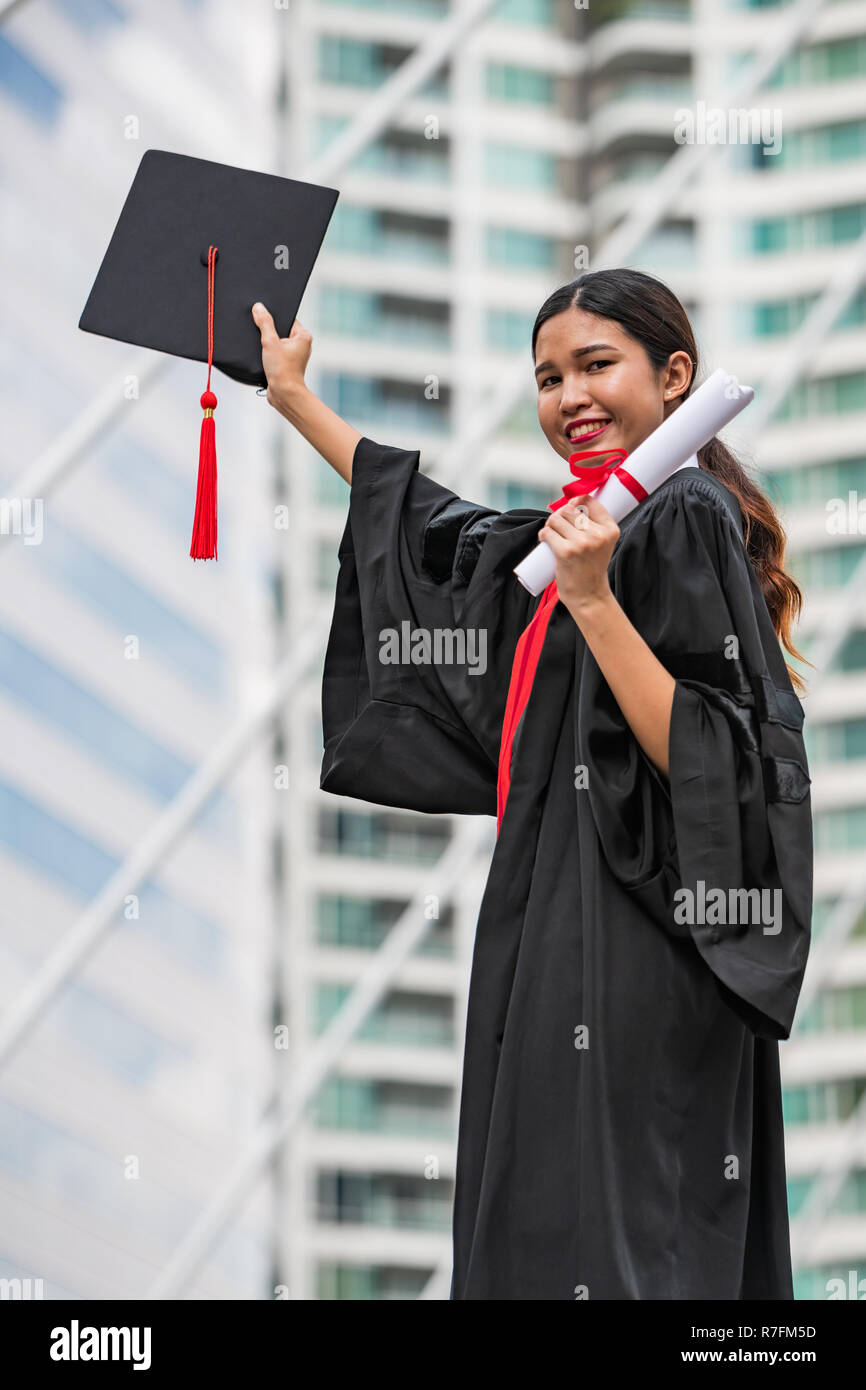 A female Asian student in graduation gown holding the diploma and graduation cap Stock Photo Alamy