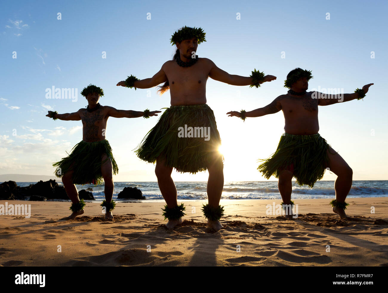 Three male hula dancers at sunset at Maui, Hawaii. Stock Photo