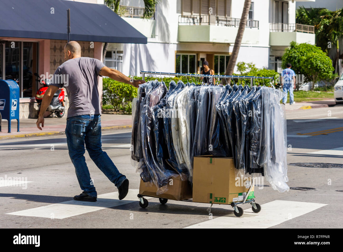 Miami Beach Florida,Collins Avenue,man men male adult adults,worker,workers,clothing,accessories,garment rack,plastic,cart,basket,trolley,pulling,cros Stock Photo