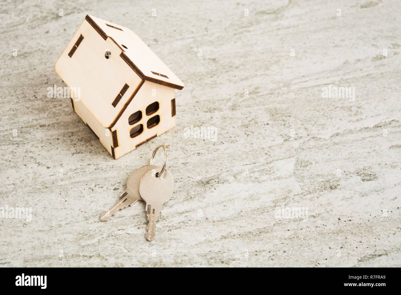 Small toy wooden house with keys on grey stone background with copy space Stock Photo