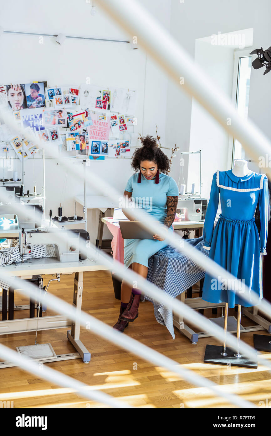 Smiling curvy African American in blue dress browsing the net Stock Photo