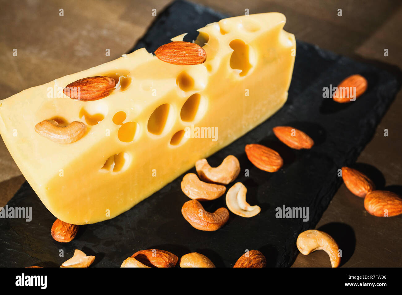 Almonds and peanuts on piece of tasty Swiss cheese Stock Photo