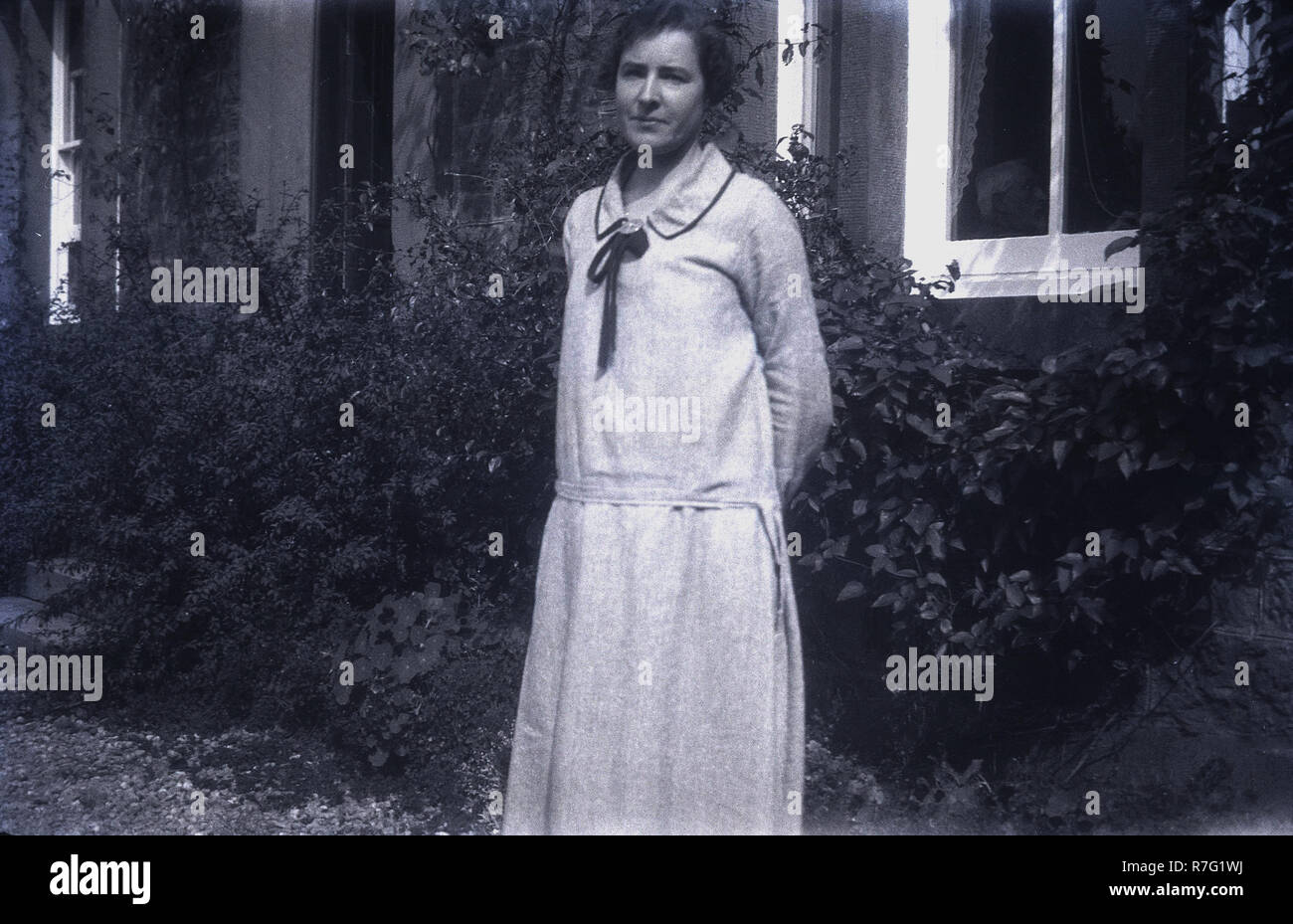 1930s, historical, a lady wearing a dress typical of the era stands outside a house Stock Photo