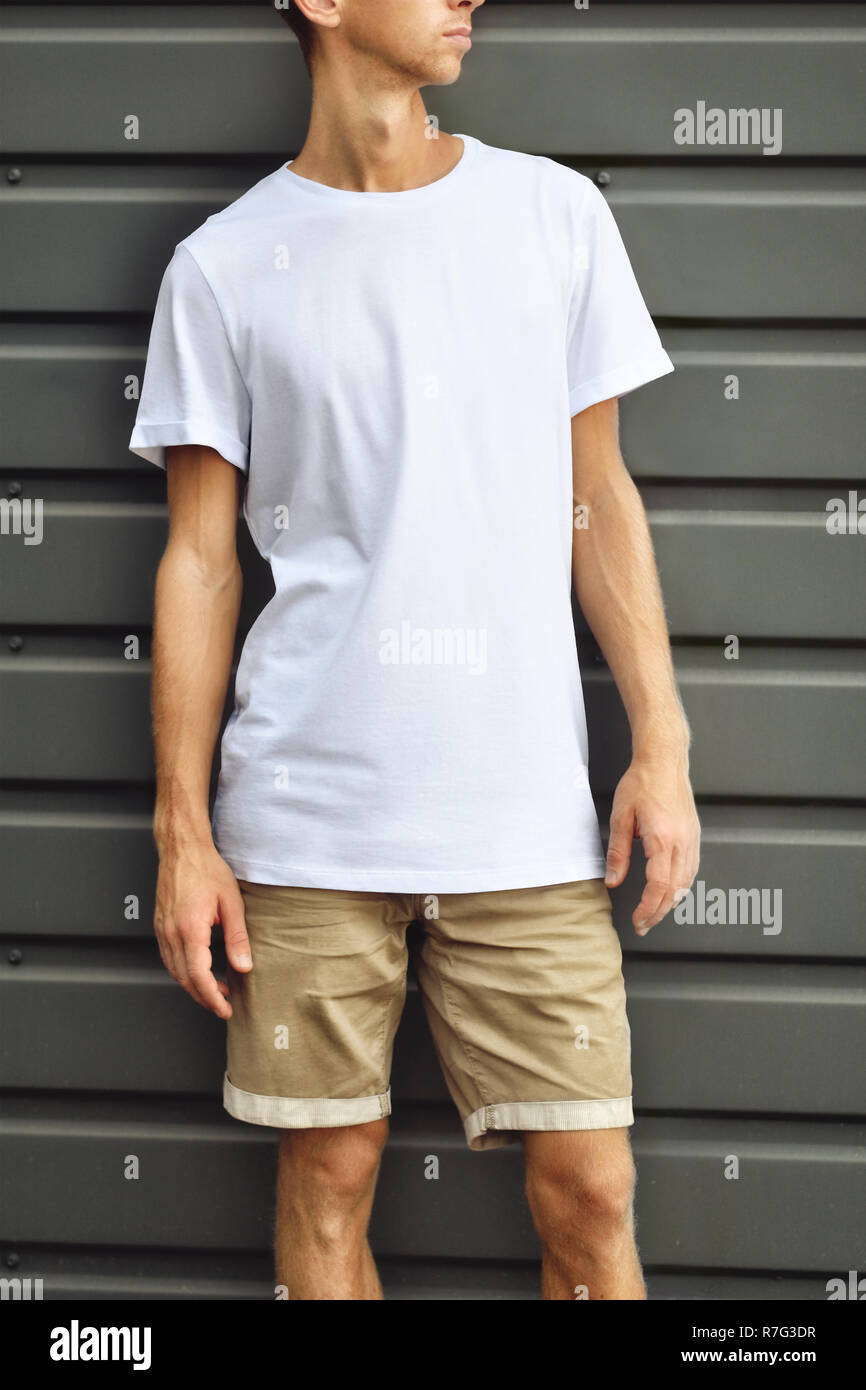 Urban template of clothes. Stylish guy standing near the gray metal  profiled wall in a blank T-shirt and brown shorts. Mockup ready for you  desig Stock Photo - Alamy