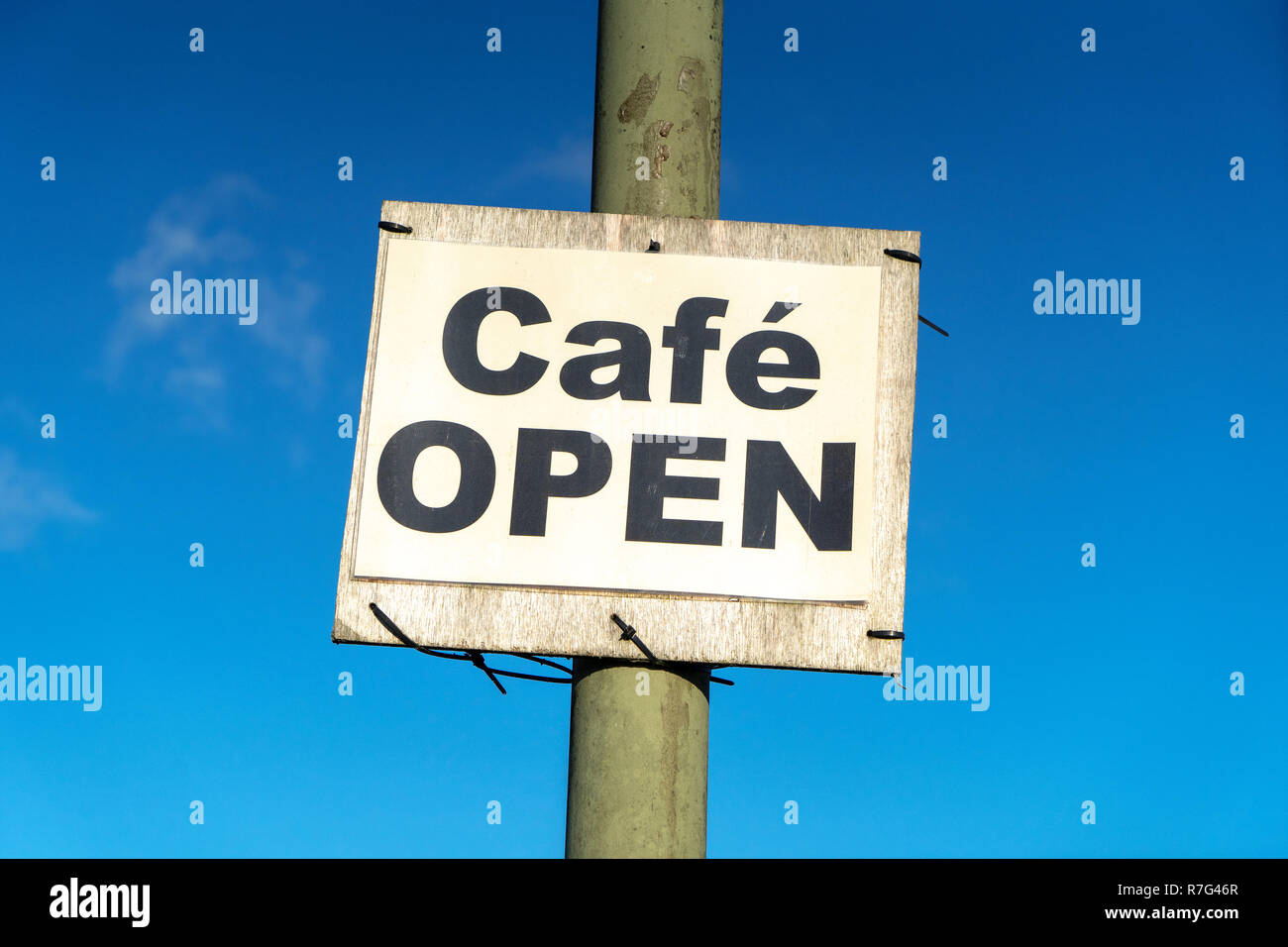 Cafe open sign on metal post against blue sky Stock Photo