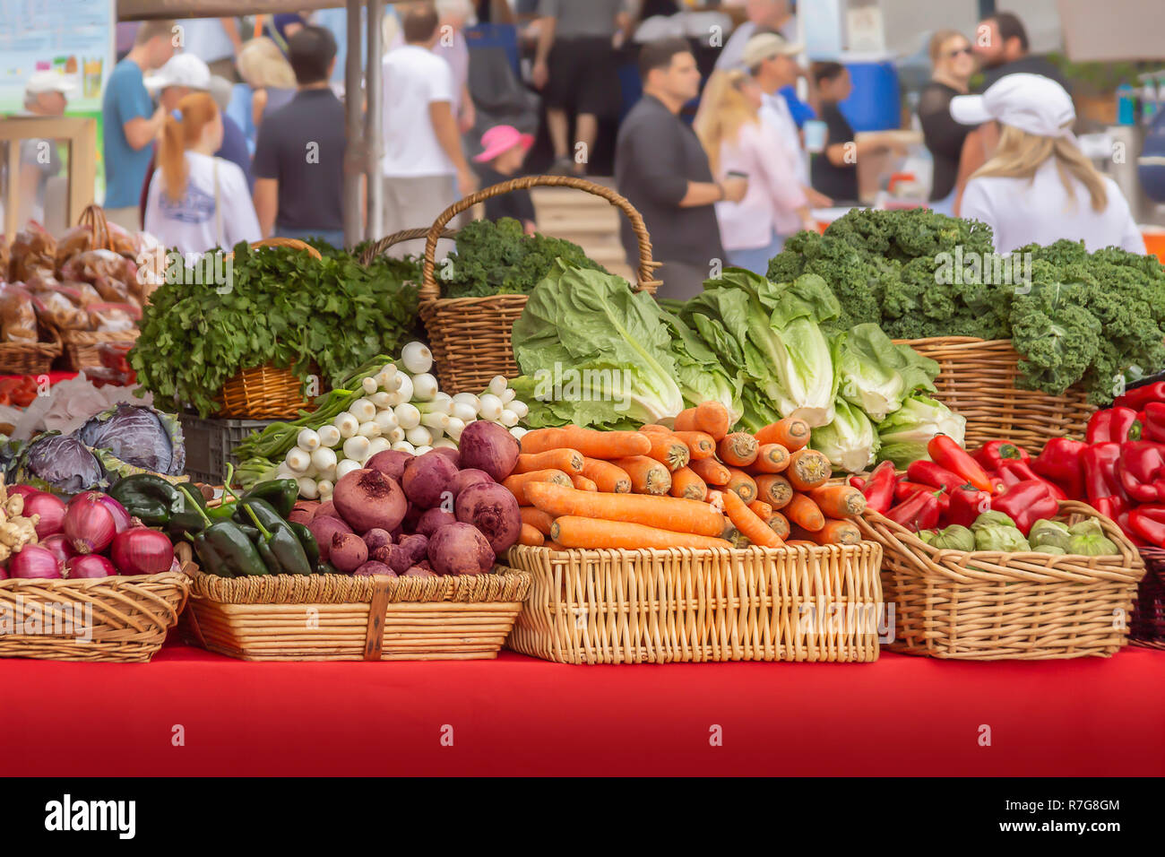 People gather on the weekends at the local outdoor farmers market. Stacked tables filled with fresh organic locally grown produce. Stock Photo