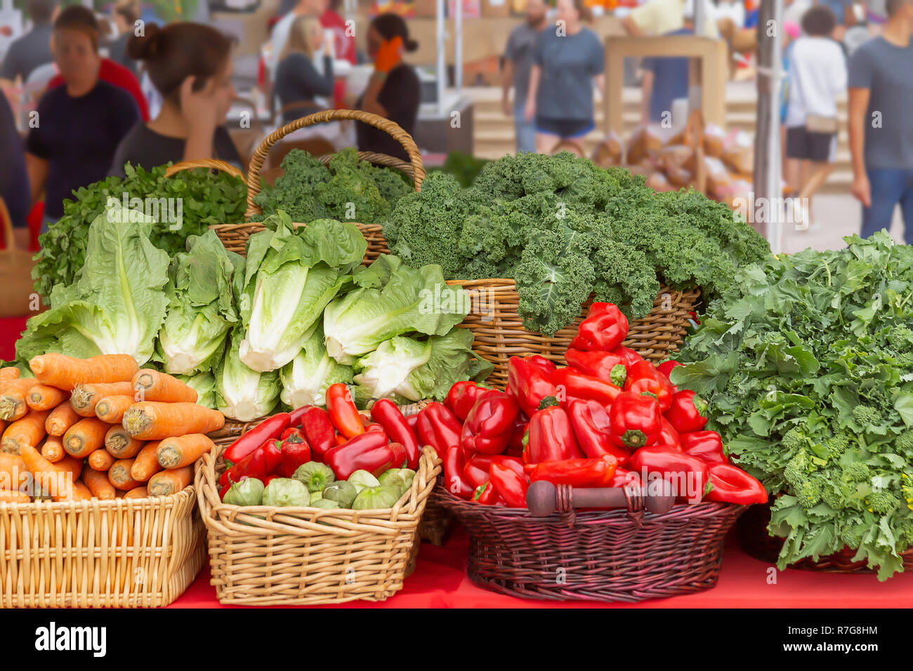 Arranged baskets are filled with red peppers, carrots, kale. a verity of greens displayed for all to see. Stock Photo