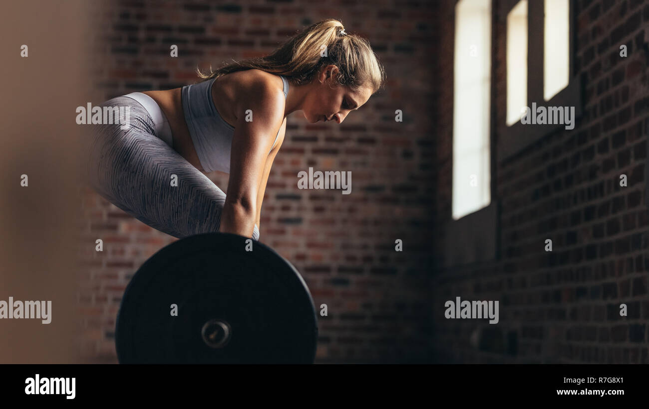 Healthy young woman lifting a barbell with heavy weights at the gym ...