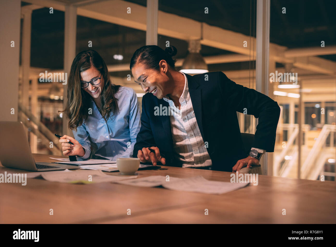 Smiling businessman and woman working together in office late in the night. business people doing work sitting late in office. Stock Photo
