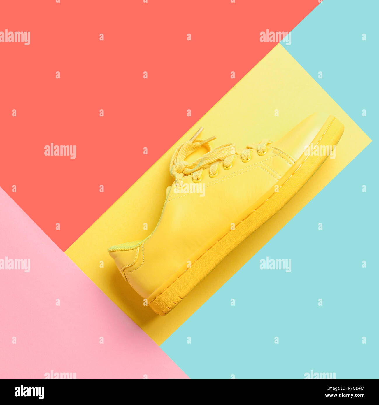 Conceptual geometric image with yellow shoe on multicolored background. Trendy colors of 2019: Living Coral, Limpet Shell, Vibrant Yellow and Sea Pink Stock Photo