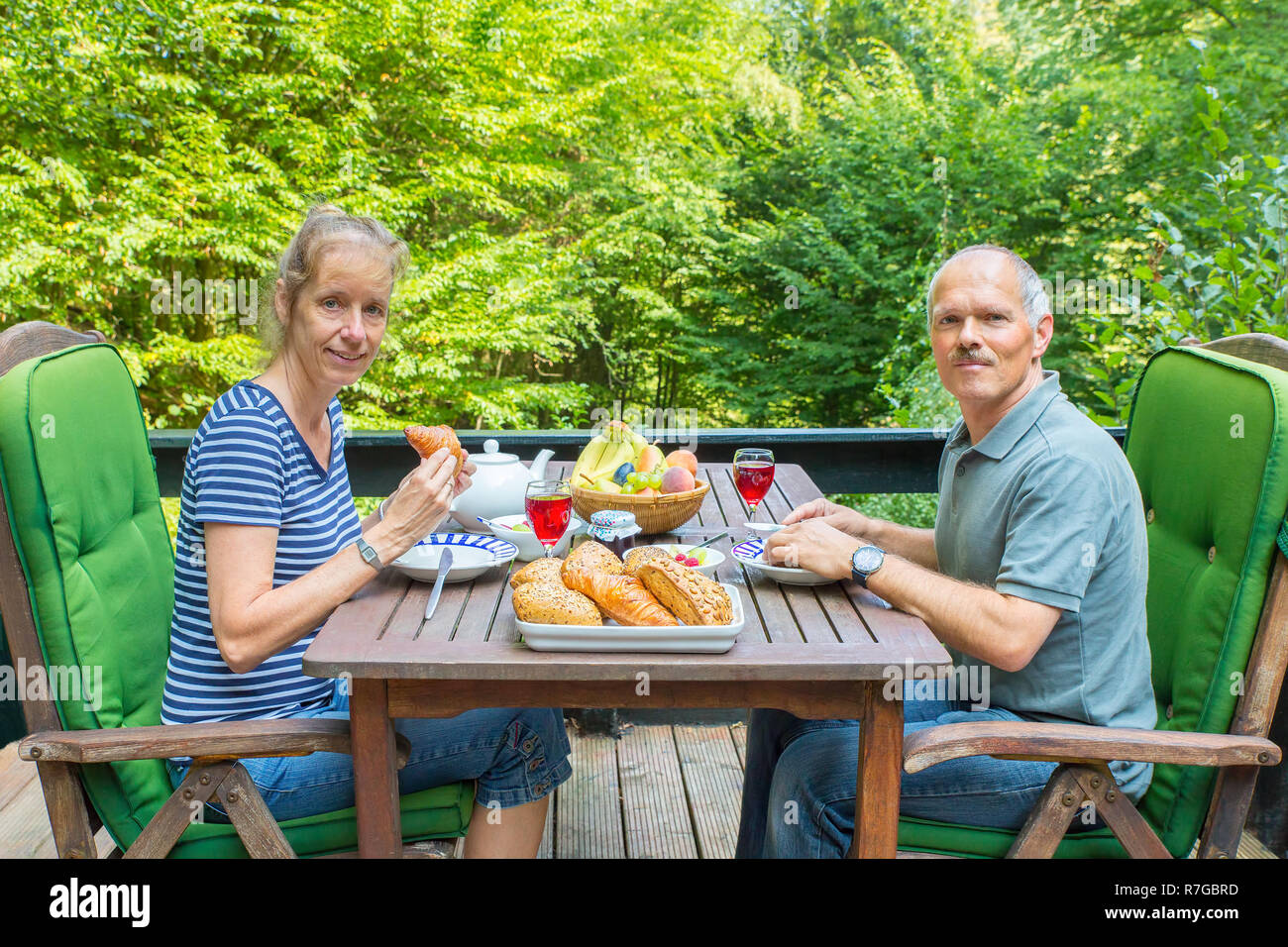 Caucasian man and woman eating lunch on terrace in nature Stock Photo