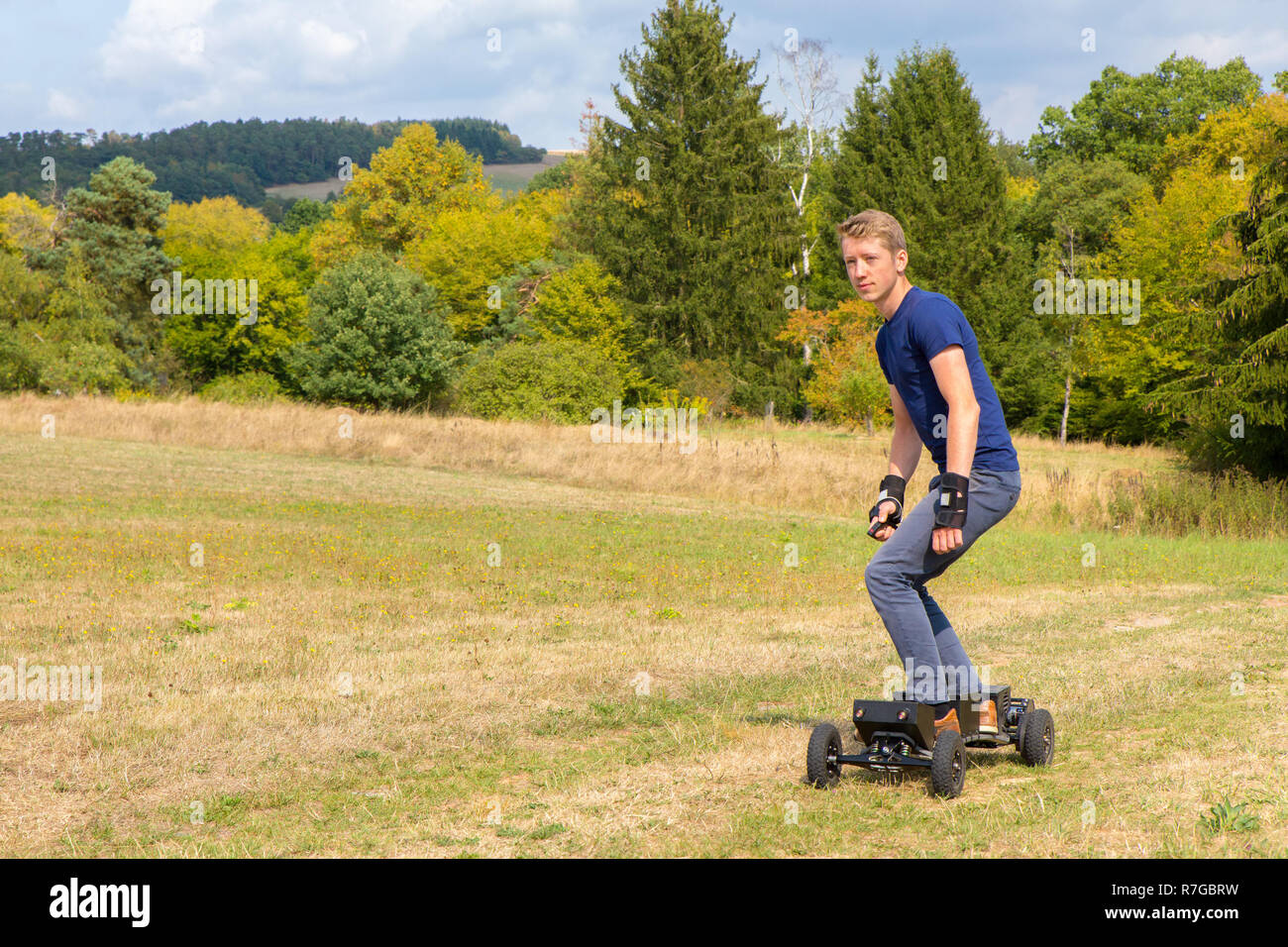 Young caucasian man rides electrical mountainboard off road in nature Stock Photo