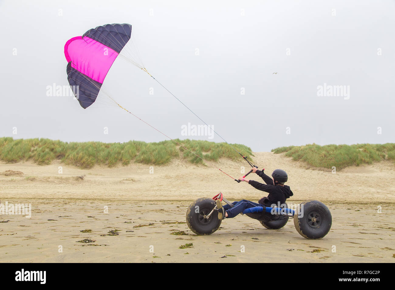 Dutch teenage boy driving kite buggy with kite flyer on beach Stock Photo