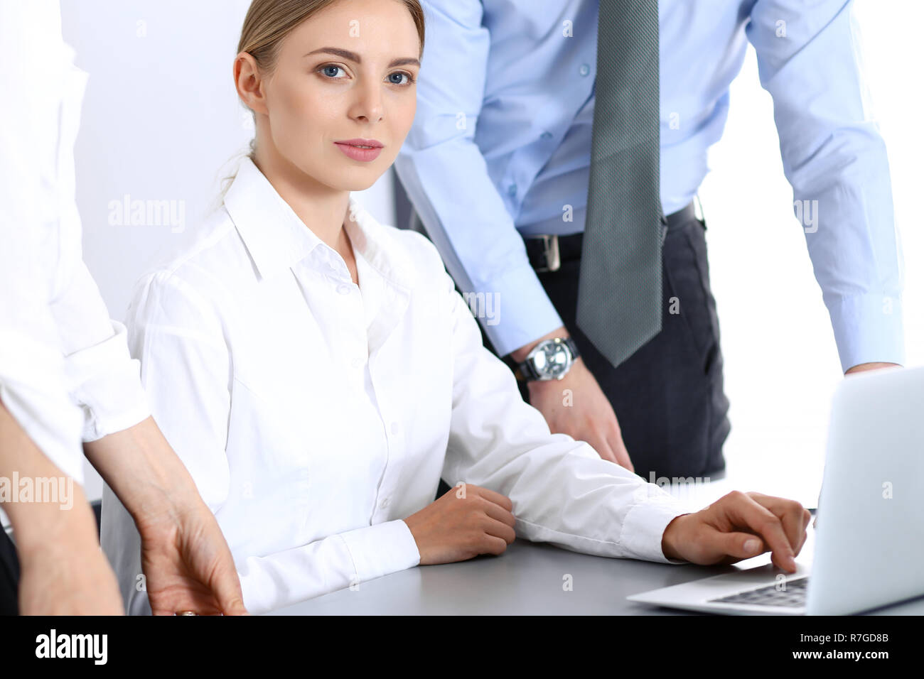 Group of business people using laptop computer while standing in office ...