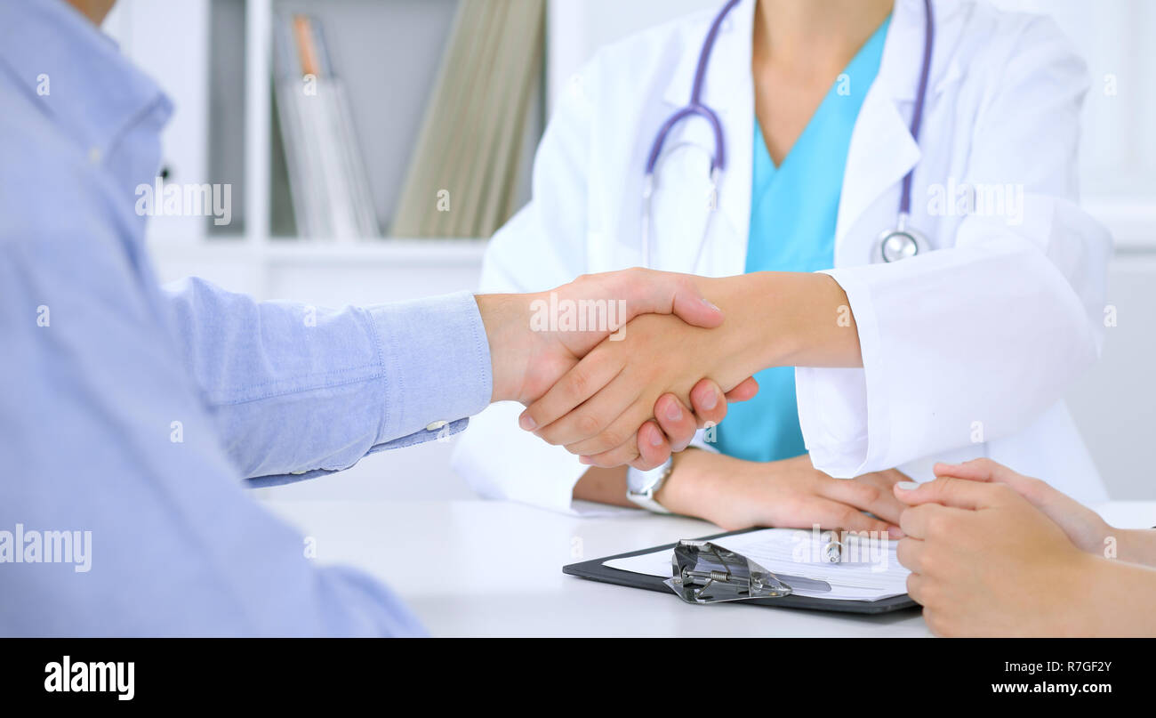 Doctor and patient shaking hands. Family couple at medical exam, just hands at the table. Medicine concept Stock Photo