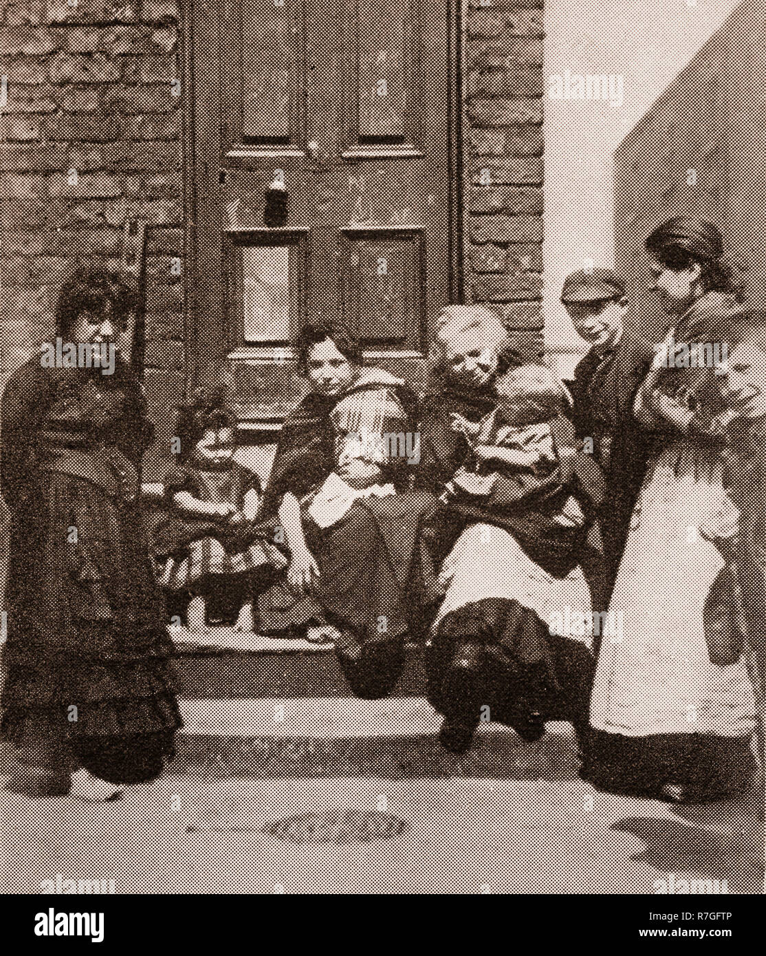 Life for working folk in Victorian days... A family sitting on the steps of their house in Curzon Street Liverpool, Merseyside, England Stock Photo