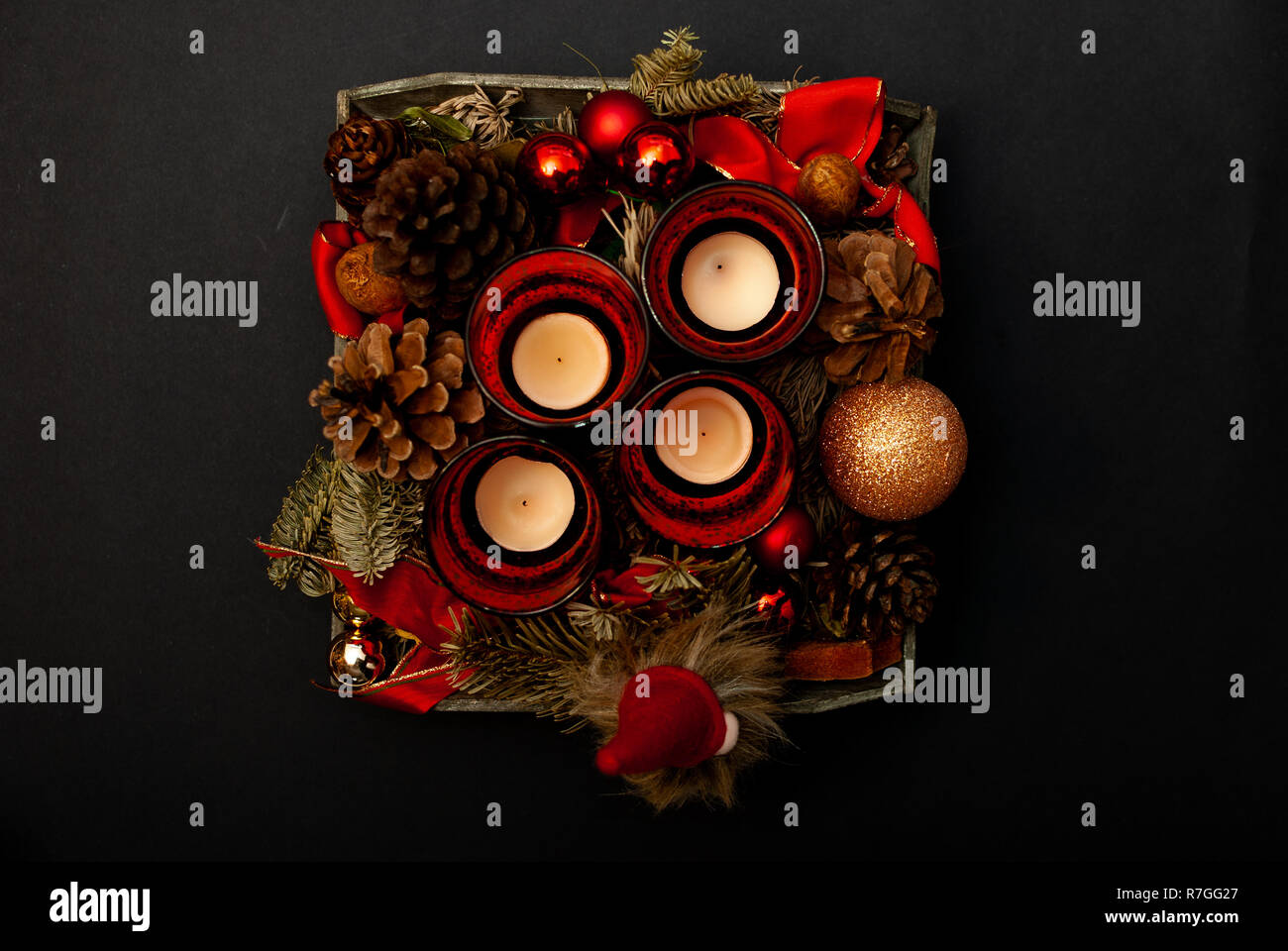 Top view of Advent wreath with four candles, fir tree, christmas balls, a dwarf and a fir cone on black background Stock Photo