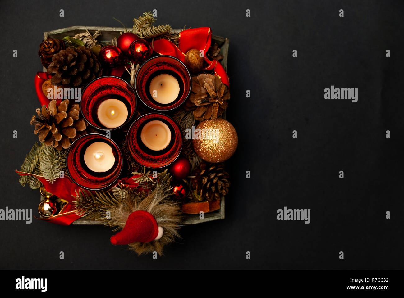 Top view of Advent wreath with four candles, fir tree, christmas balls, a dwarf and a fir cone on black background Stock Photo