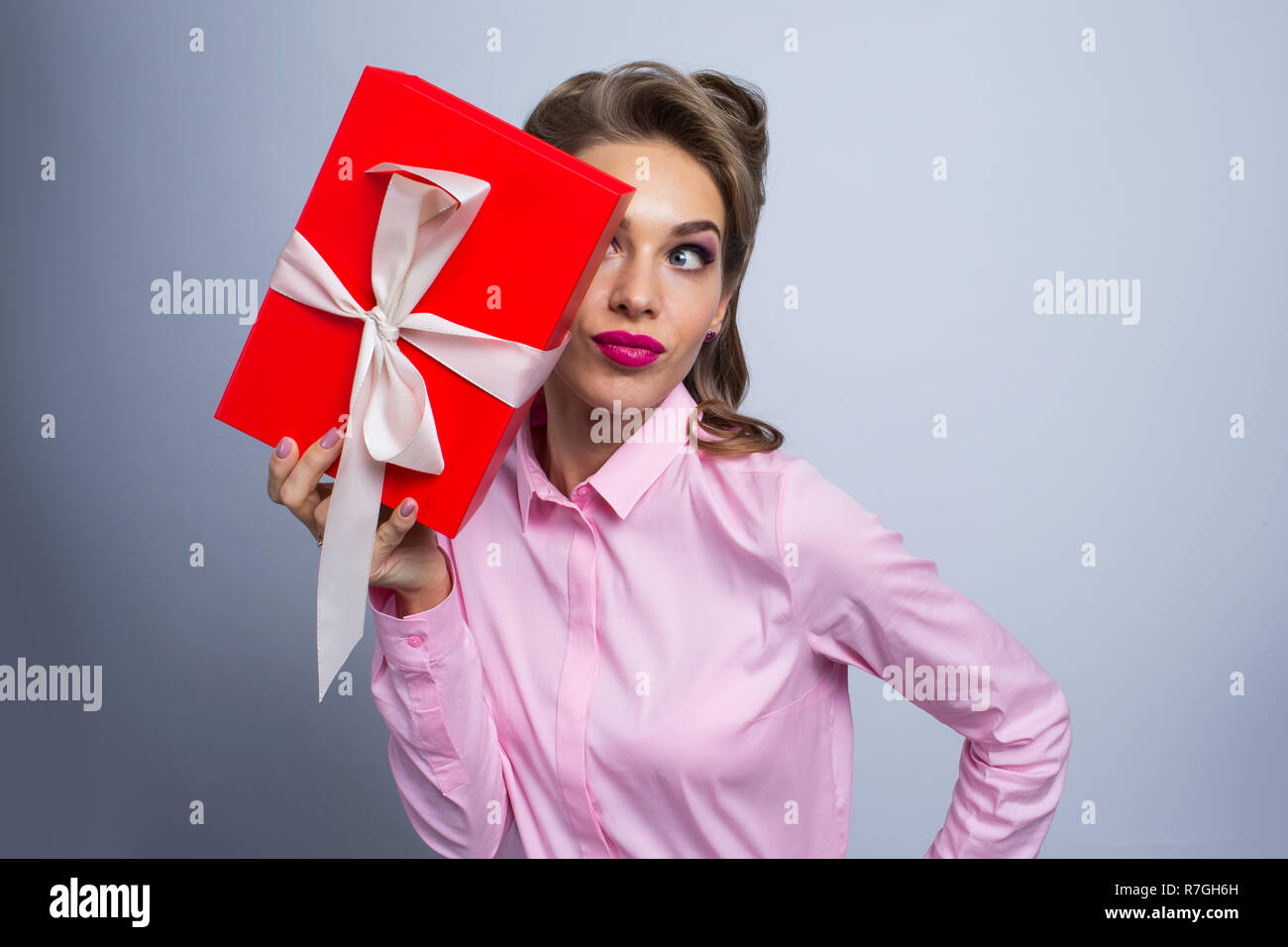 Happy beautiful funny woman holding gift box, listening Stock Photo