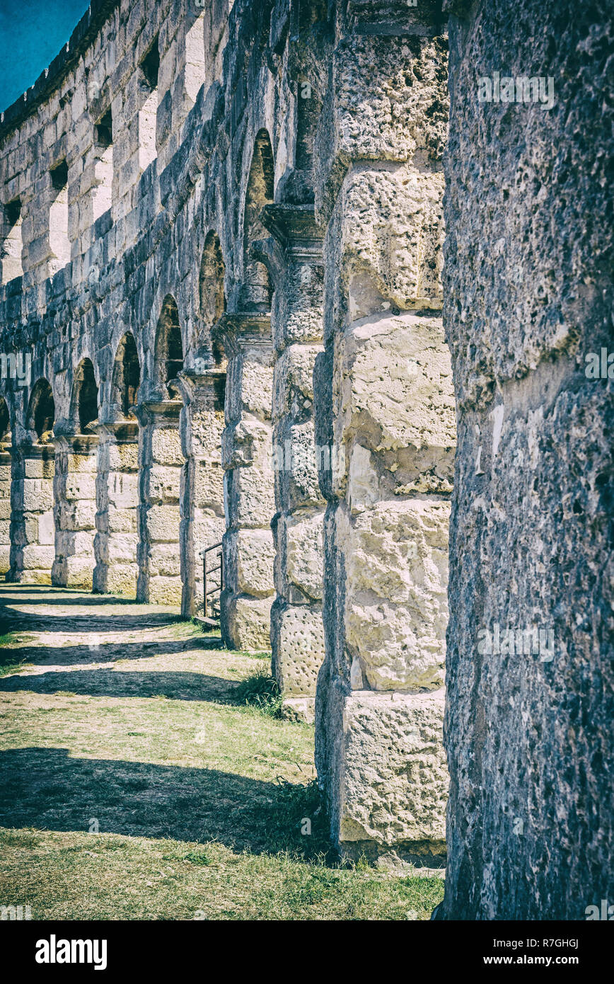 Detail photo of Pula Arena, Istria, Croatia. Travel destination. Ancient architecture. Vertical composition. Analog photo filter with scratches. Stock Photo