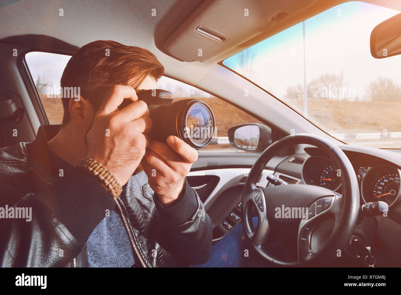 A man is taking pictures from a car window. Photographer traveler. The work of a private detective. Stock Photo