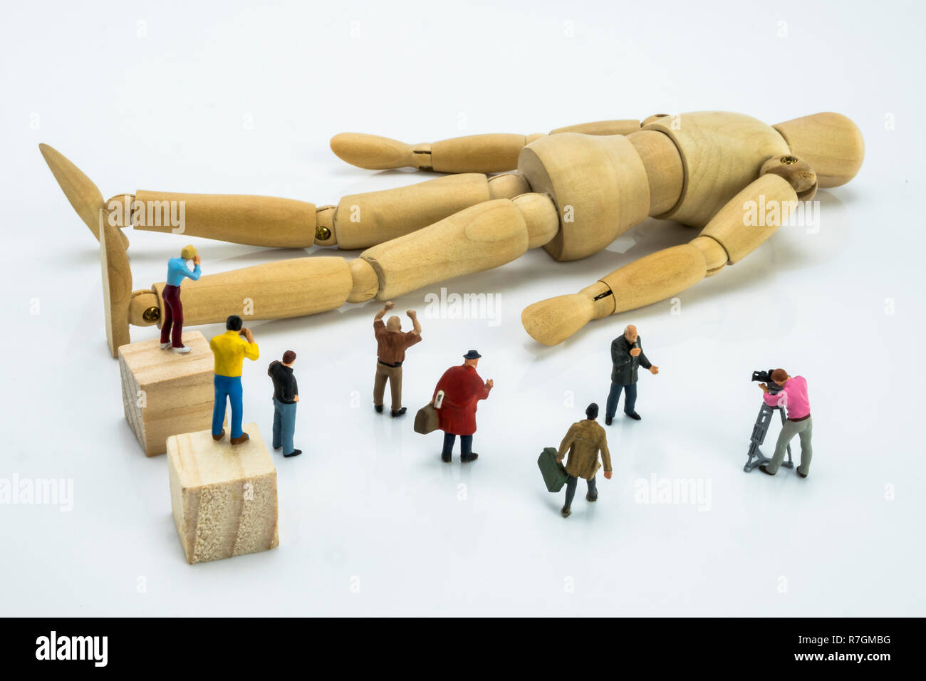 Miniature figures surrounding wood doll, conceptual image Stock Photo