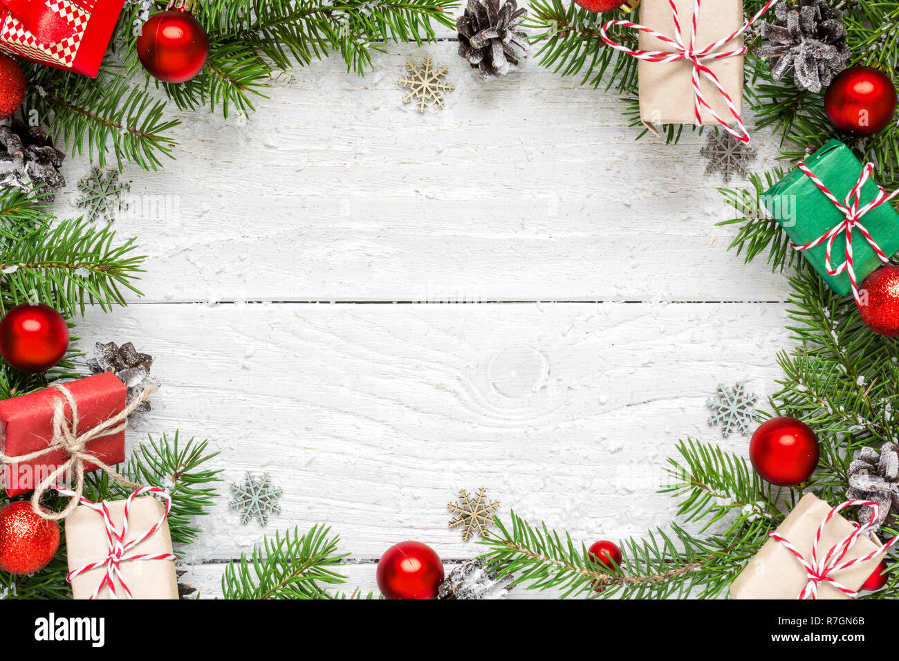 Christmas frame made of fir branches, festive decorations, gift boxes and pine cones on white wooden table. Christmas background. Flat lay. top view w Stock Photo
