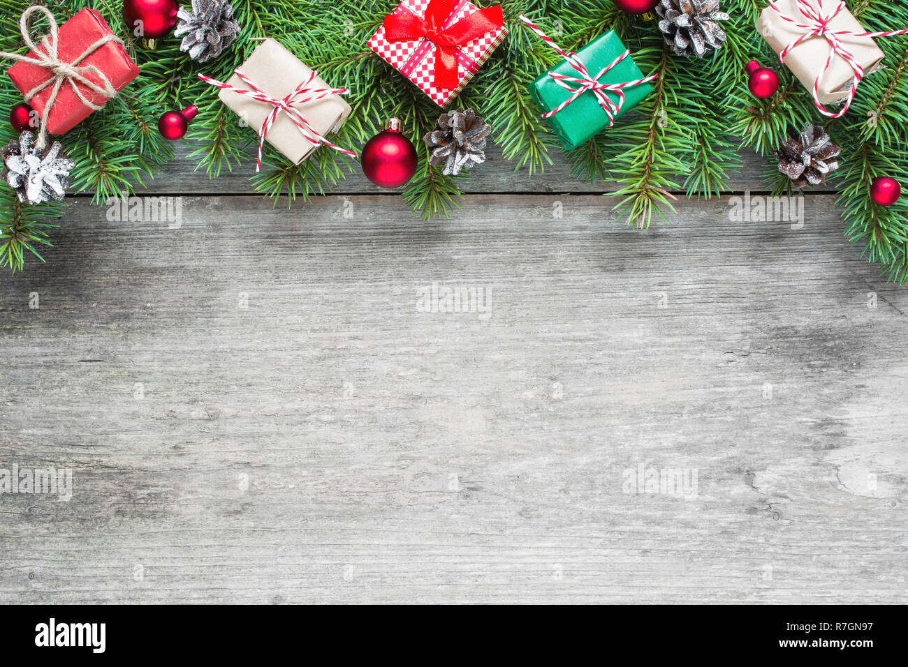 Christmas background with fir branches, decorations, gift boxes and pine cones on rustic wooden table. Christmas background. Flat lay. top view with c Stock Photo