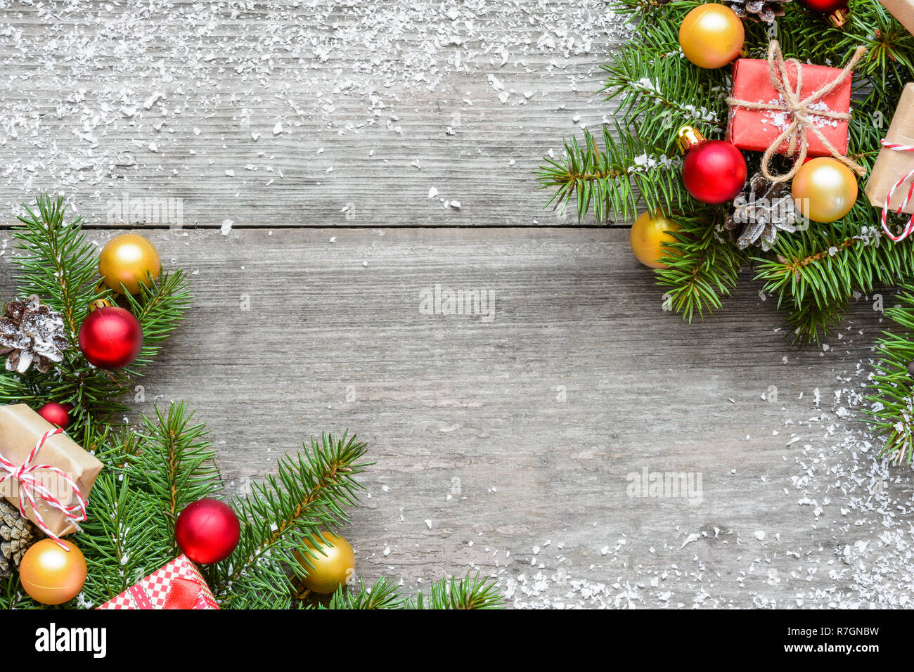 Christmas background with fir branches, decorations, gift boxes and pine cones on rustic wooden table covered with snow. Christmas background. Flat la Stock Photo