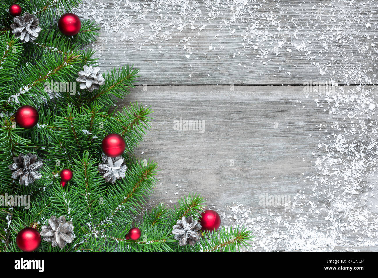 Christmas background with fir tree branches, red decorations and pine cones on rustic wooden table covered with snow. Flat lay. top view with copy spa Stock Photo