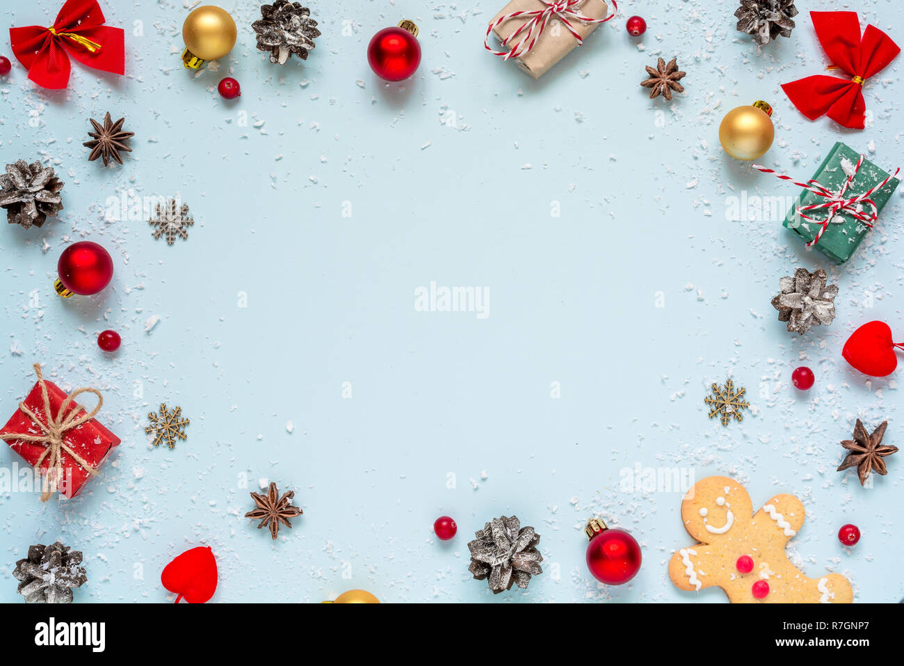 Christmas composition. frame made of christmas decorations, red berries, gift boxes and pine cones on blue background. Christmas background. Flat lay. Stock Photo