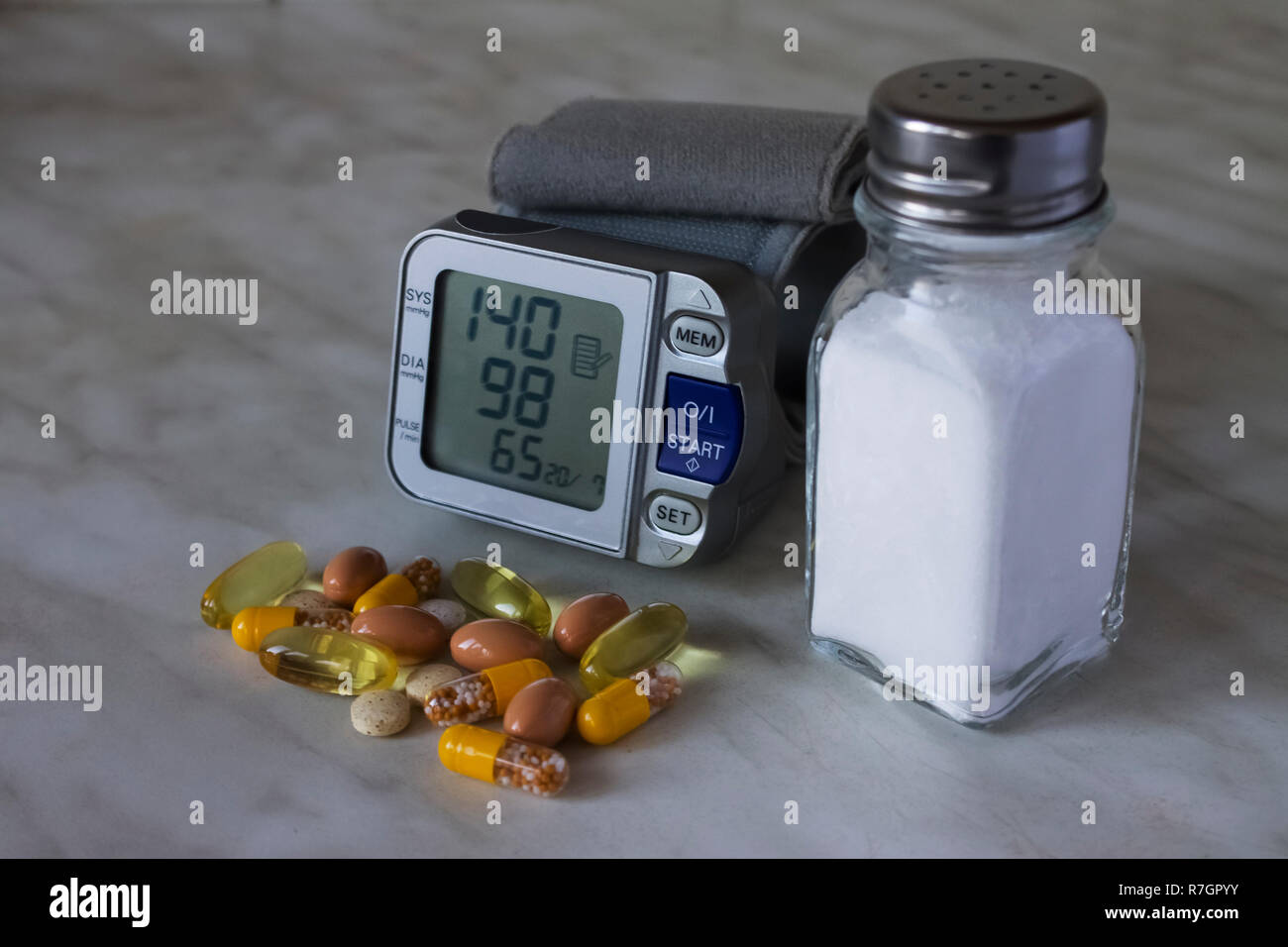 Blood pressure meter,saltcellar and the pills on the white kitchen